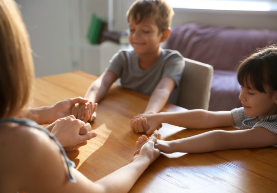 Kinder am Tisch reichen sich die Hände
